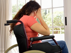 A person in a wheelchair holding their head. 