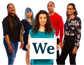 A group of people, one person is standing at the front holding a sign saying 'We'.