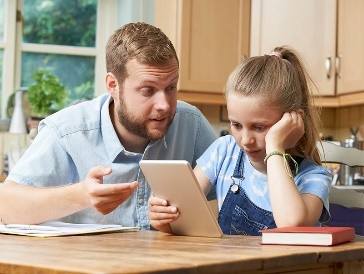 Someone looking at what their child is doing on a digital tablet. 