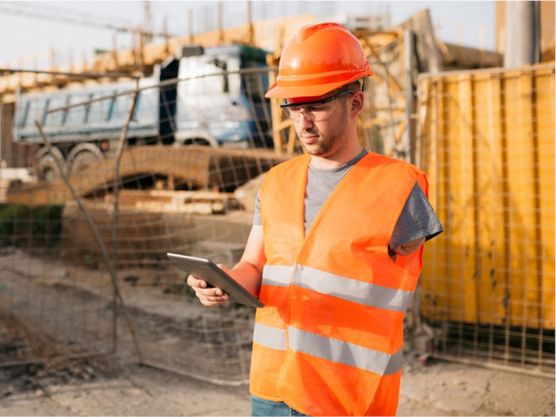 A person with disability wearing high visibility clothes and safety equipment working on a construction site.