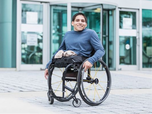 A person with a physical disability using a wheelchair to get around a city.