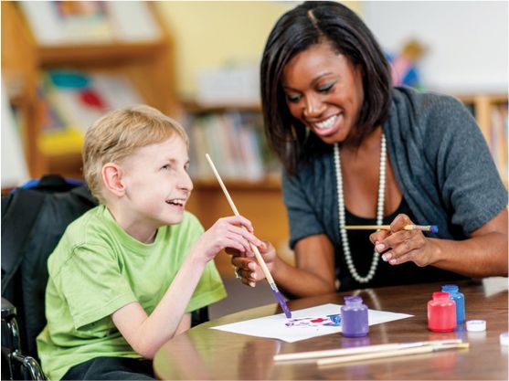 A teacher supporting a student with a painting.