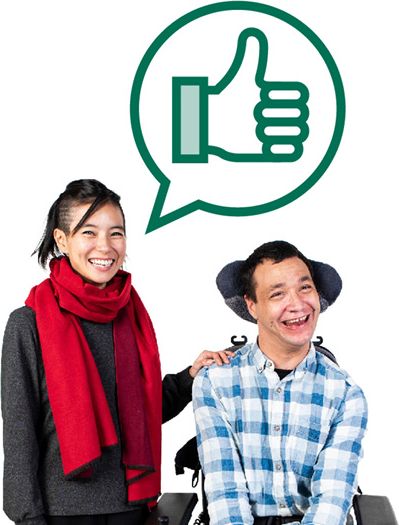 A person supporting someone with disability. Both of them are happy. The person giving support has a speech bubble with a thumbs up in it.