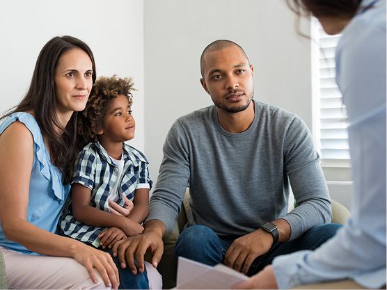 A carer having a conversation with a family of 3.