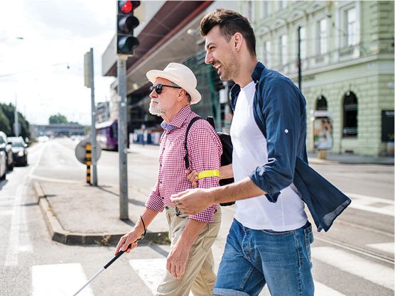 A person with disability crossing the street with someone else.