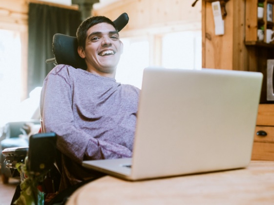 A person in a wheelchair using a laptop. 