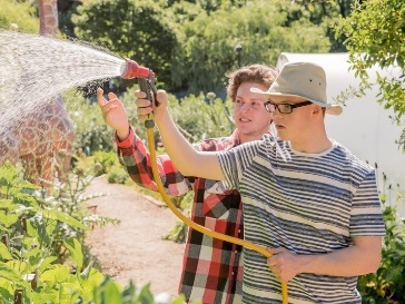 A person supporting someone to water the garden.