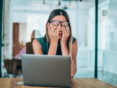  A person using a laptop and looking upset.