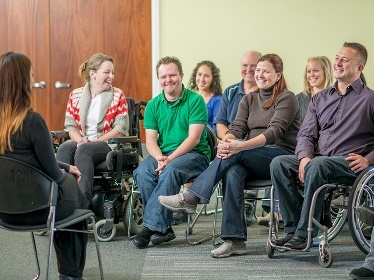 A group of people in a meeting. 2 of the people are in wheelchairs.