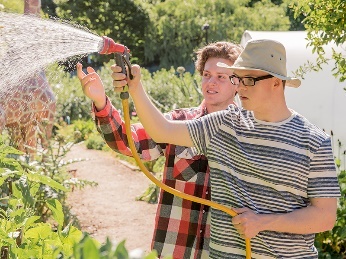 A person with disability watering a community garden.