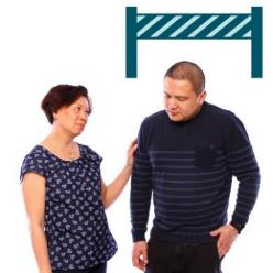 A person supporting someone else, with a barrier behind them.