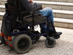 A photo of a person in a wheelchair next to some stairs.